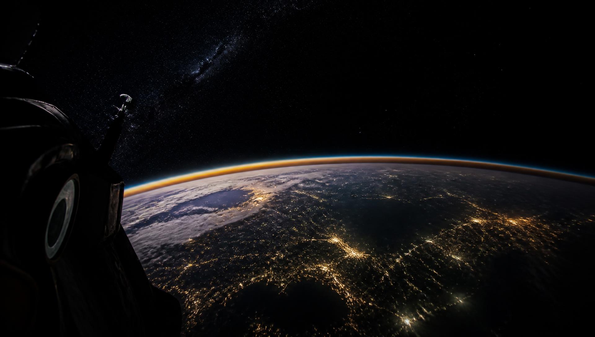 View from orbit of Earth at night with the glowing edge of the atmosphere